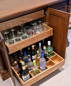 an open cabinet filled with lots of bottles and glasses on top of a carpeted floor