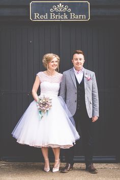 a man and woman standing next to each other in front of a black barn sign