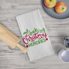 a kitchen towel that says baking christmas memories next to two apples and a rolling pin