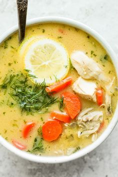 a white bowl filled with chicken, carrots and lemon