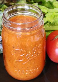 a jar filled with sauce next to tomatoes and lettuce