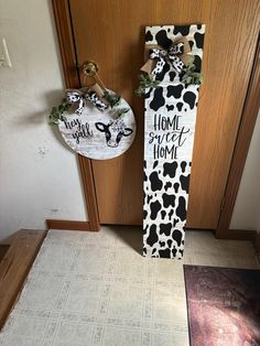 a door hanger that says home sweet home and a cow print sign hanging on the front door