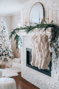 stockings hanging from the mantle in front of a christmas tree and fireplace with candles on it