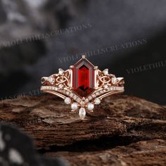 a ring with a red stone surrounded by white diamonds on top of a wooden surface