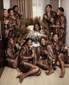 a group of bridesmaids posing for a photo in brown robes and flower bouquets