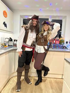 a man and woman dressed up as pirates posing for a photo in the kitchen together