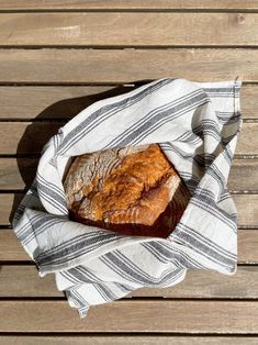 a loaf of bread sitting on top of a white and black towel next to a wooden table