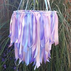 purple and blue streamers hanging from the side of a plant in front of some tall grass