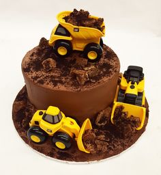 there is a chocolate cake decorated with construction vehicles on the top and dirt around it