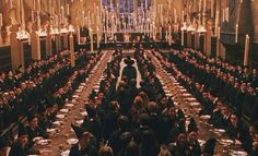 a large group of people sitting at long tables in a room with chandeliers