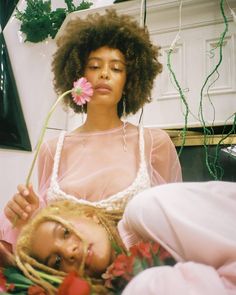 a woman holding a flower in front of her face with another woman's head