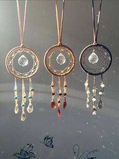 three dream catchers hanging from the ceiling with crystal beads and chains attached to them