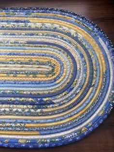 a blue and yellow round rug on top of a wooden floor