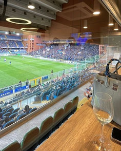 a large stadium filled with lots of people sitting at tables and watching something in the distance