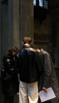 two people standing next to each other near a pillar