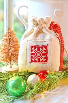 a small white bag sitting on top of a table next to christmas ornaments and decorations