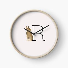 a clock with the letter r on it's face and a rabbit sitting in front of it