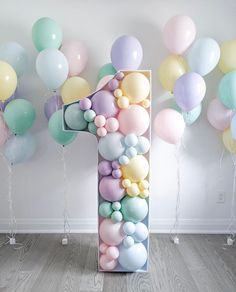 a number one made out of balloons in front of a white wall and wooden floor