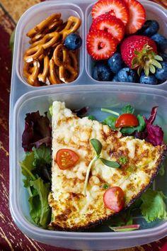 a plastic container filled with lots of food next to pretzels and strawberries