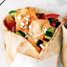 two wraps filled with meat and vegetables on top of a white countertop next to each other