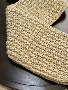 a pair of beige knitted ties sitting on top of a wooden table