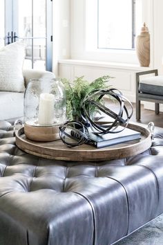 a coffee table with a candle and some books on it in a living room area