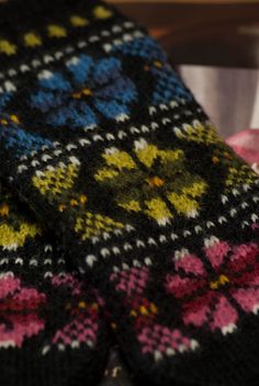 a colorful knitted tie laying on top of a wooden table next to a pink blanket