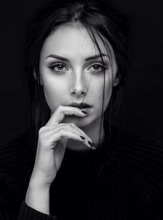 a black and white photo of a woman with her hand on her chin looking at the camera