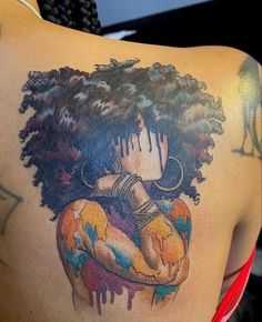 the back of a woman's shoulder with an afro girl tattoo on her upper arm