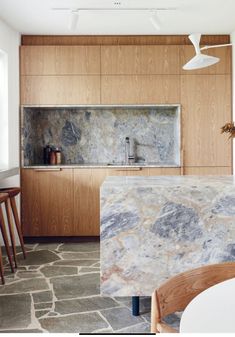 a kitchen with marble counter tops and wooden cabinets in the back drop off area, along with bar stools