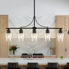 a kitchen with marble counter tops and an island in front of the stove top, surrounded by bar stools