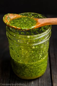 a jar filled with green pestle and a wooden spoon