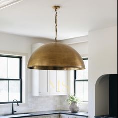 a kitchen with white cabinets and black countertops has a gold dome light hanging from the ceiling