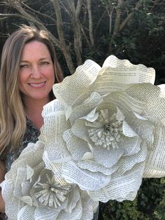 a woman holding up a large paper flower