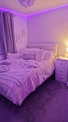 a bedroom with purple lighting and white furniture