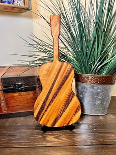 a wooden guitar sitting next to a potted plant