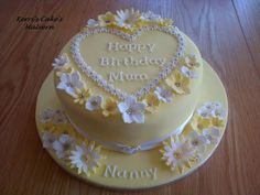 a heart shaped cake with daisies and the words happy birthday mum written on it