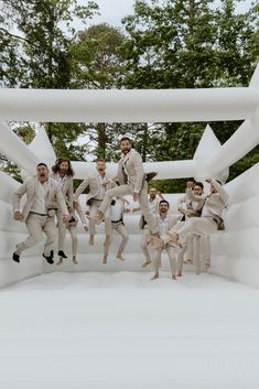 a group of men in suits jumping into the air on an inflatable structure