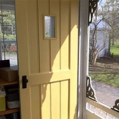 a yellow door is open in front of a window