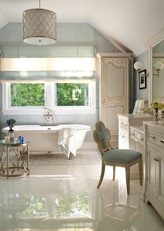 a large bathroom with a tub, sink and chair in it's center area