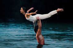 a man doing a handstand in the water while holding another man's leg