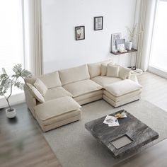 a living room with a large sectional couch and coffee table in the middle, along with pictures on the wall