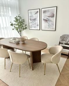 a dining room table and chairs in front of two pictures on the wall above it