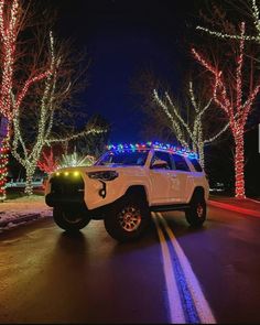 a white truck driving down a street covered in christmas lights