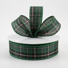 a green and black plaid ribbon with a bow on the top, sitting on a white box