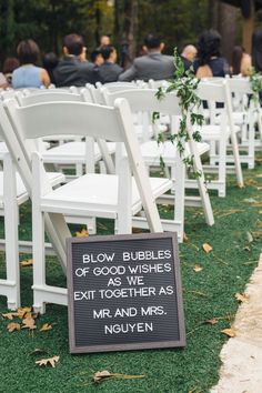 rows of white chairs with signs on them in front of an outdoor wedding ceremony area