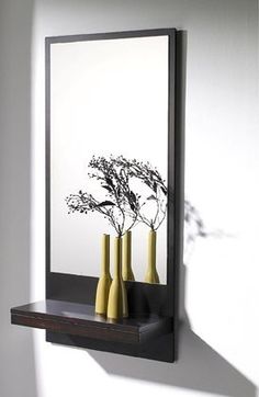 two vases with flowers are on a shelf in front of a mirror that is reflecting the wall