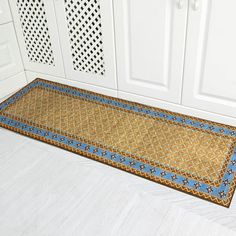 a blue and gold rug in the corner of a kitchen next to white cupboards