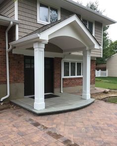 a house with a covered porch in front of it and brick walkway leading up to the front door