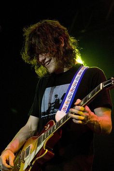 a young man playing a guitar on stage